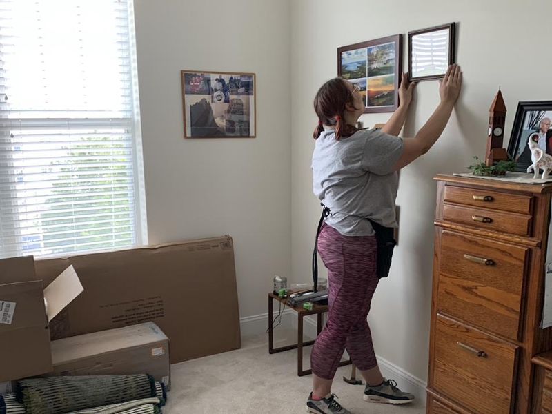 A team member hanging artwork in a client’s new home